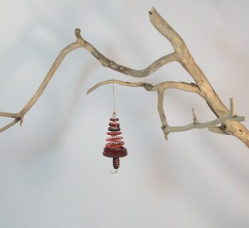 Branche sèche sur laquelle est accroché un sapin formé par des boutons rouges empilés du plus grand en bas au plus petit en haut et surmonté d'une perle. De petites perles sont intercalées entre les boutons pour leur donner un peu de hauteur et un côté dansant. Une perles en bois suggère le tronc. Une ficelle dorée permet de le suspendre.