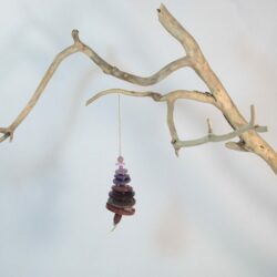 Branche sèche sur laquelle est accroché un sapin formé par des boutons violets empilés du plus grand en bas au plus petit en haut et surmonté d'une perle. De petites perles sont intercalées entre les boutons pour leur donner un peu de hauteur et un côté dansant. Une perles en bois suggère le tronc. Une ficelle dorée permet de le suspendre.