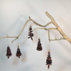 Branche sèche sur laquelle sont suspendus des sapins formés par des boutons violets empilés du plus grand en bas au plus petit en haut et surmonté d'une perle. De petites perles sont intercalées entre les boutons pour leur donner un peu de hauteur et un côté dansant. Des perles en bois suggèrent les troncs. Une ficelle dorée permet de les suspendre.
