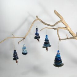 Branche sèche sur laquelle sont suspendus des sapins formés par des boutons bleus empilés du plus grand en bas au plus petit en haut et surmonté d'une perle. De petites perles sont intercalées entre les boutons pour leur donner un peu de hauteur et un côté dansant. Des perles en bois suggèrent les troncs. Une ficelle dorée permet de les suspendre.